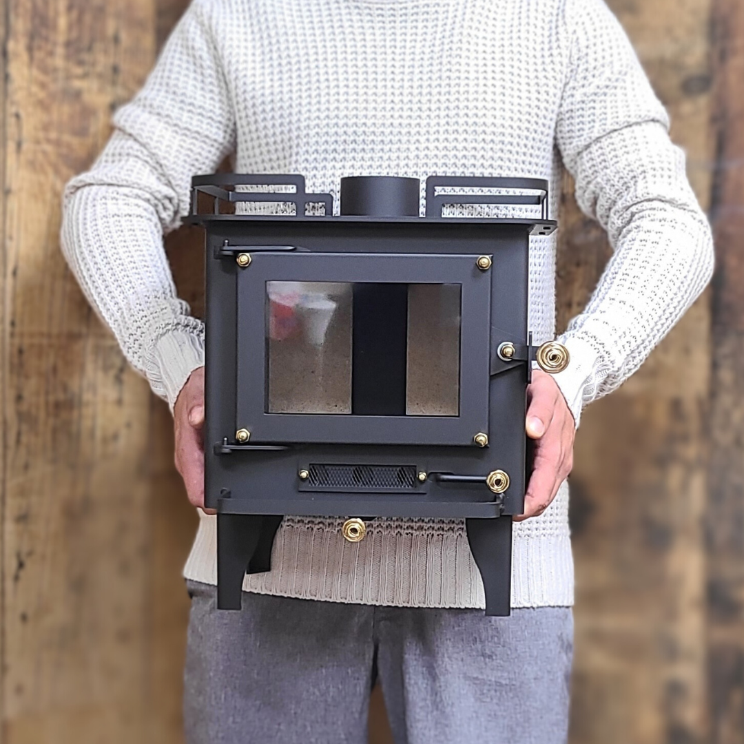 CB-2000 Grizzly black wood stove with a visible firebox and brass plated coil handles. Held in arms